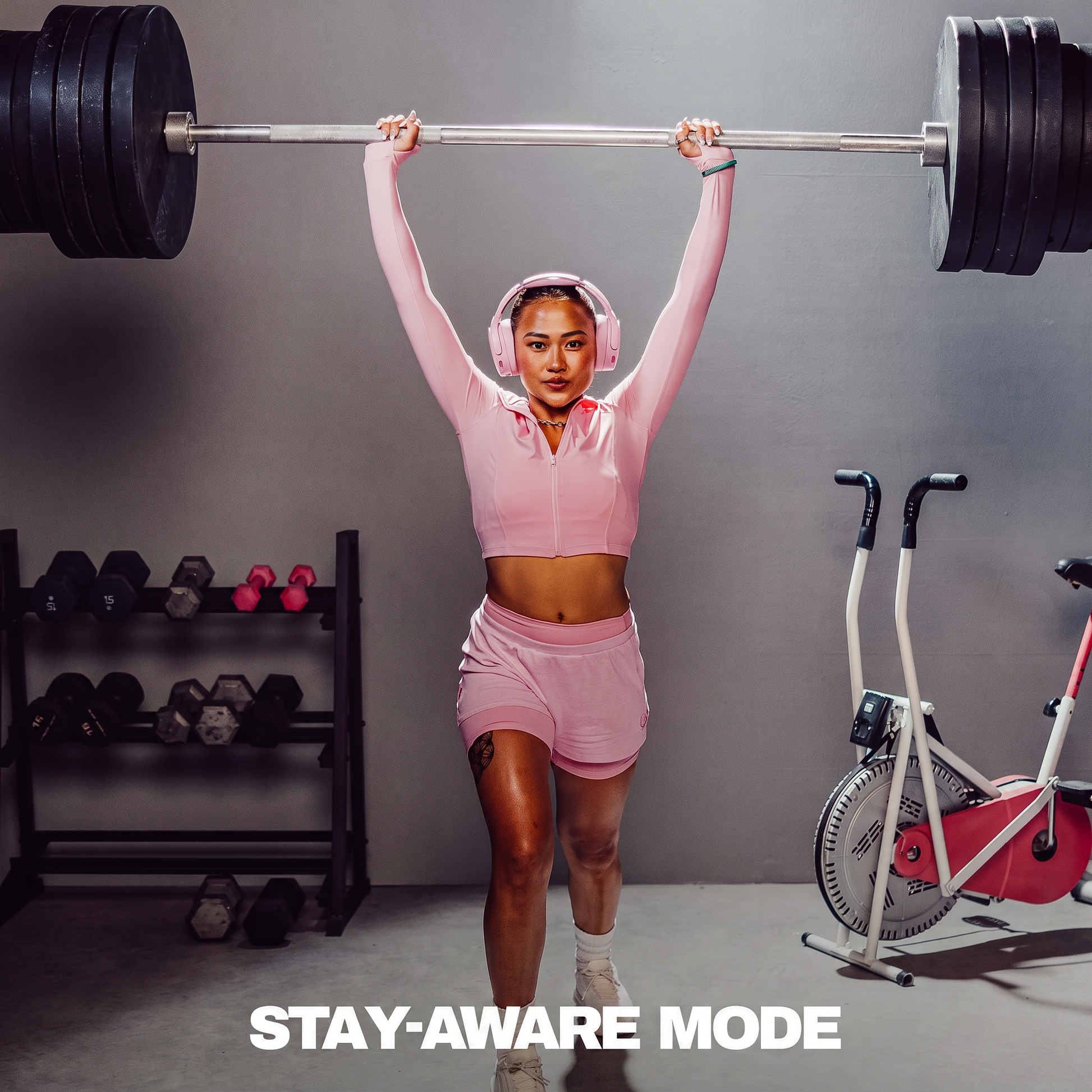 Person lifting a barbell with gym equipment in the background | Candy