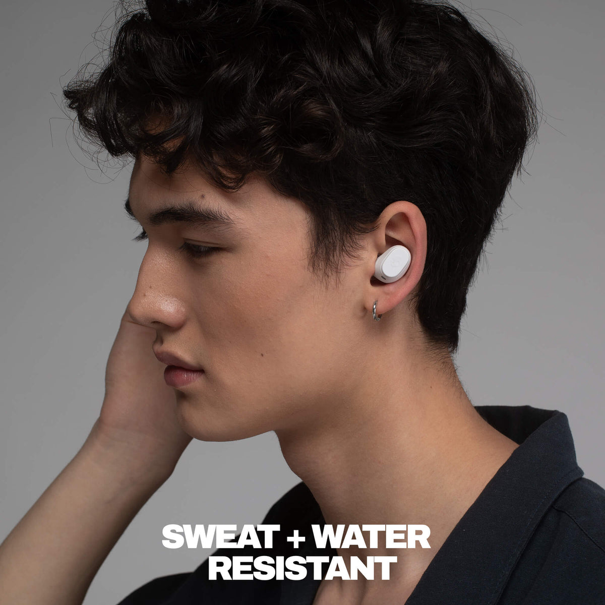 Person wearing a sweat and water-resistant earbud with text on a gray background | Bone
