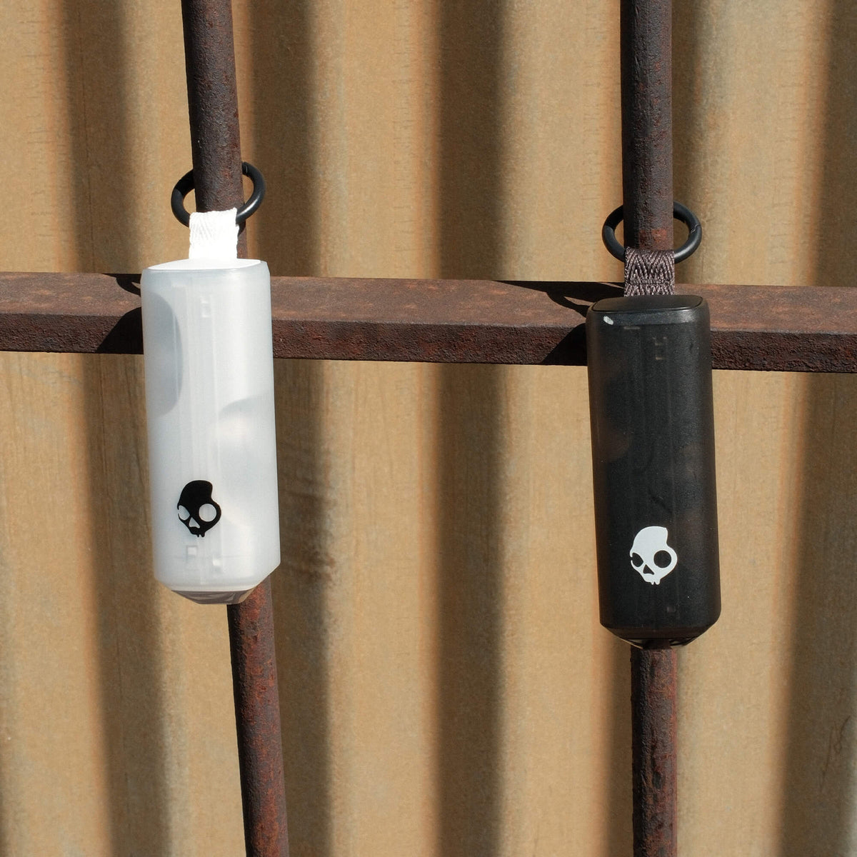 Two noisemakers hanging on a rusty metal bar against a corrugated metal background. | Bone