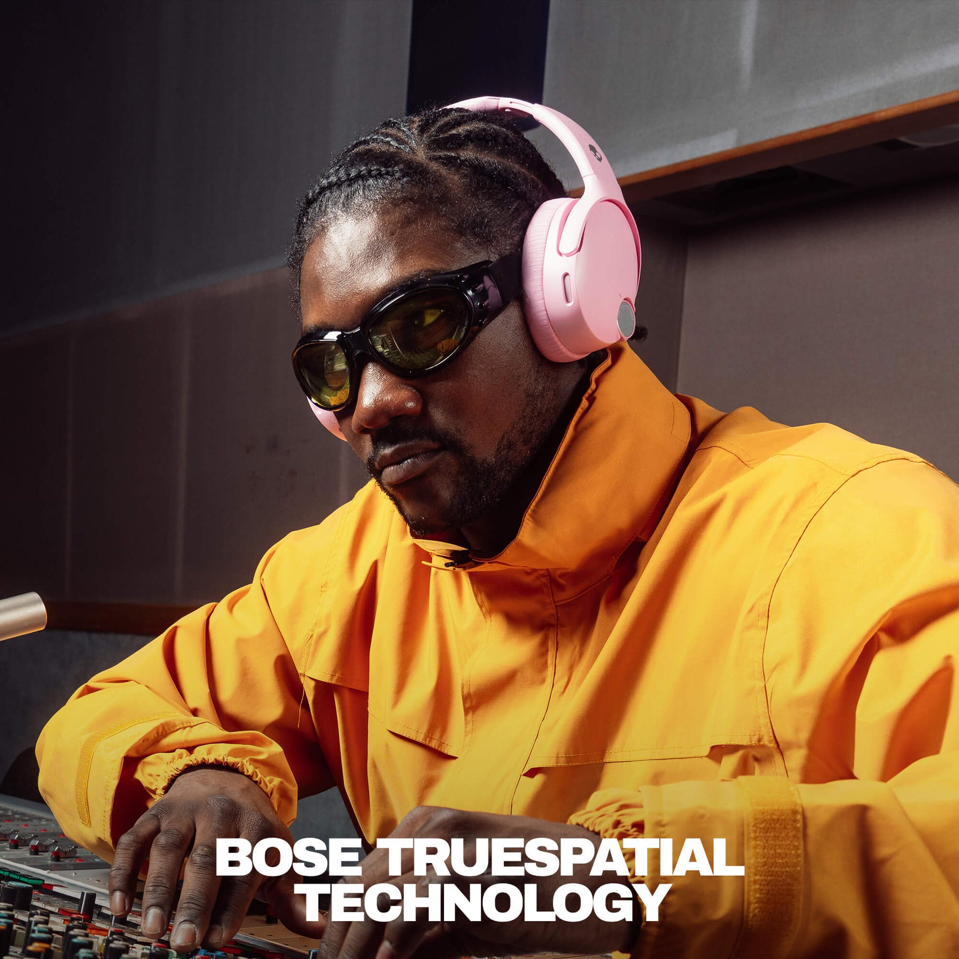 Person wearing pink headphones and sunglasses, sitting at a mixing console with 'Bose TrueSpacial Technology' text. | Candy
