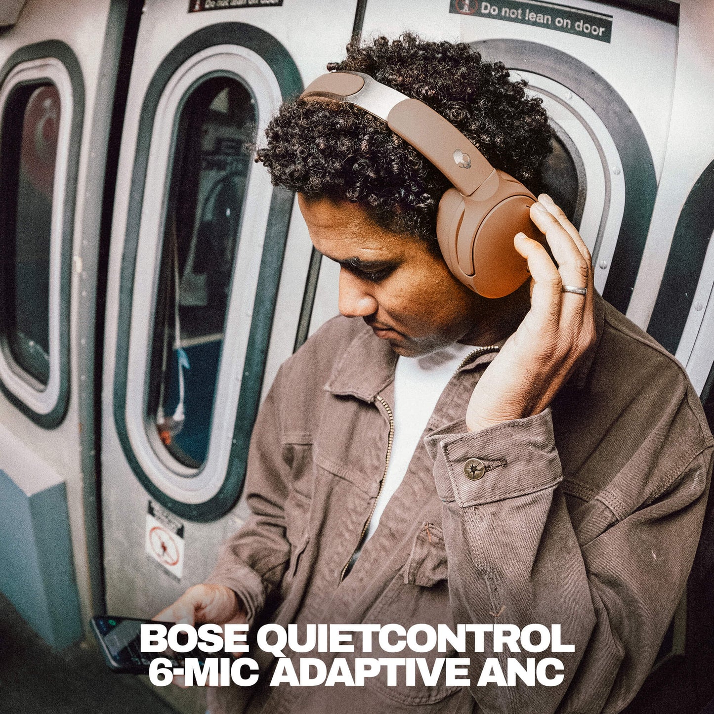 Person wearing Skullcandy Bose QuietControl headphones on a subway train, with product name displayed. | Primer