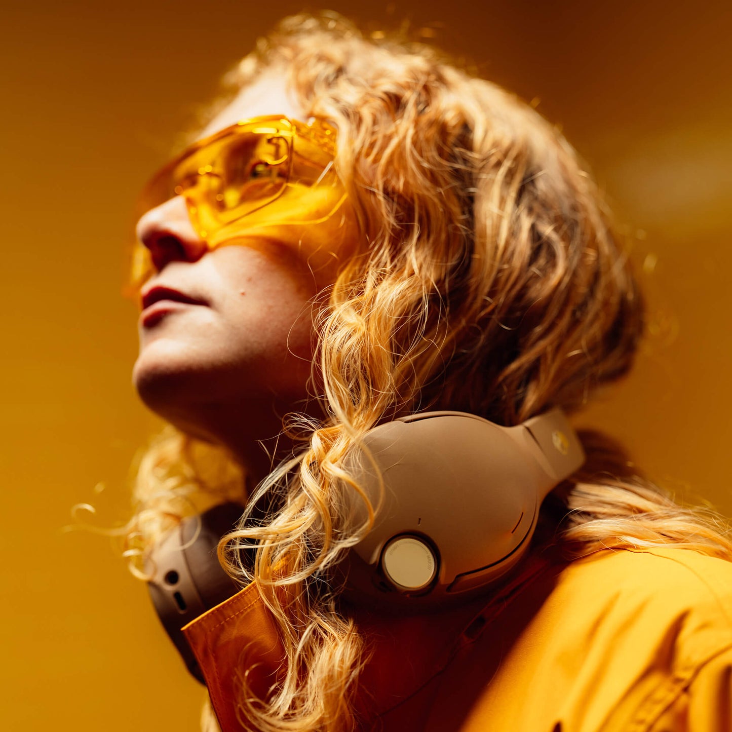 Person wearing yellow sunglasses and headphones against a warm-toned background | Primer