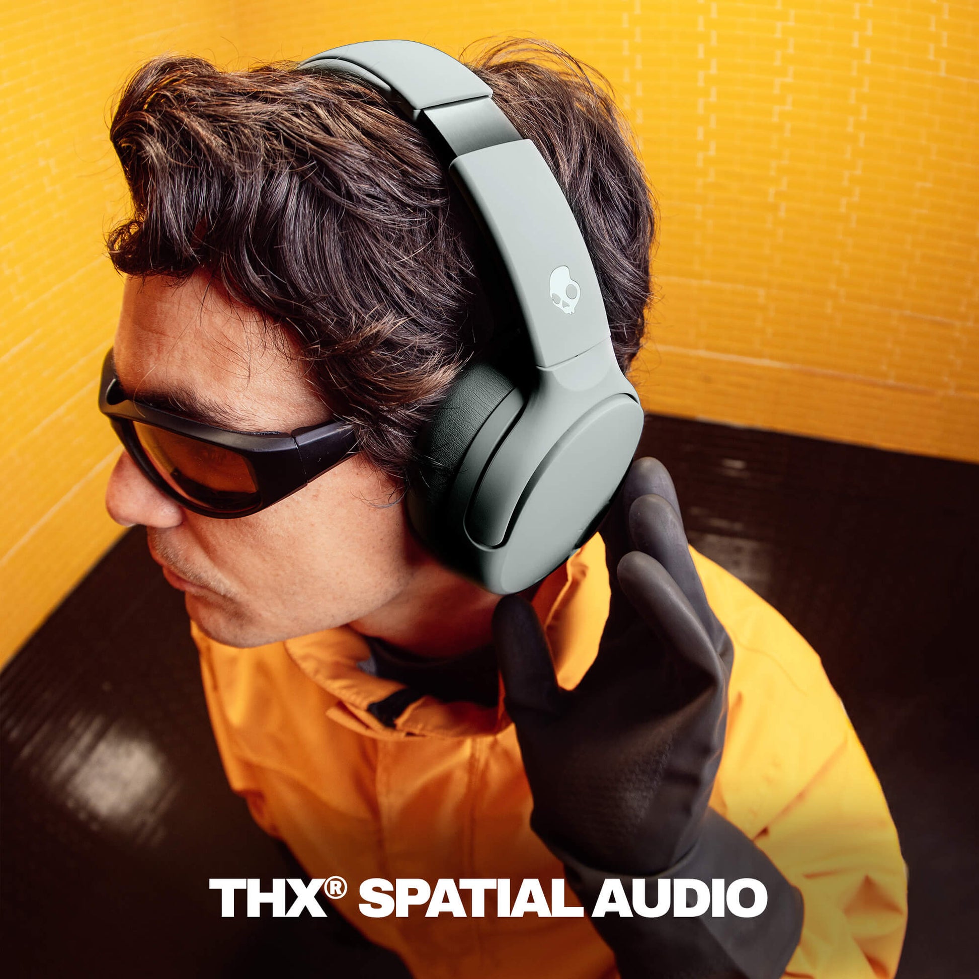 Person wearing Crusher 720 headphones with 'THX Spatial Audio' text on a yellow background | Cement