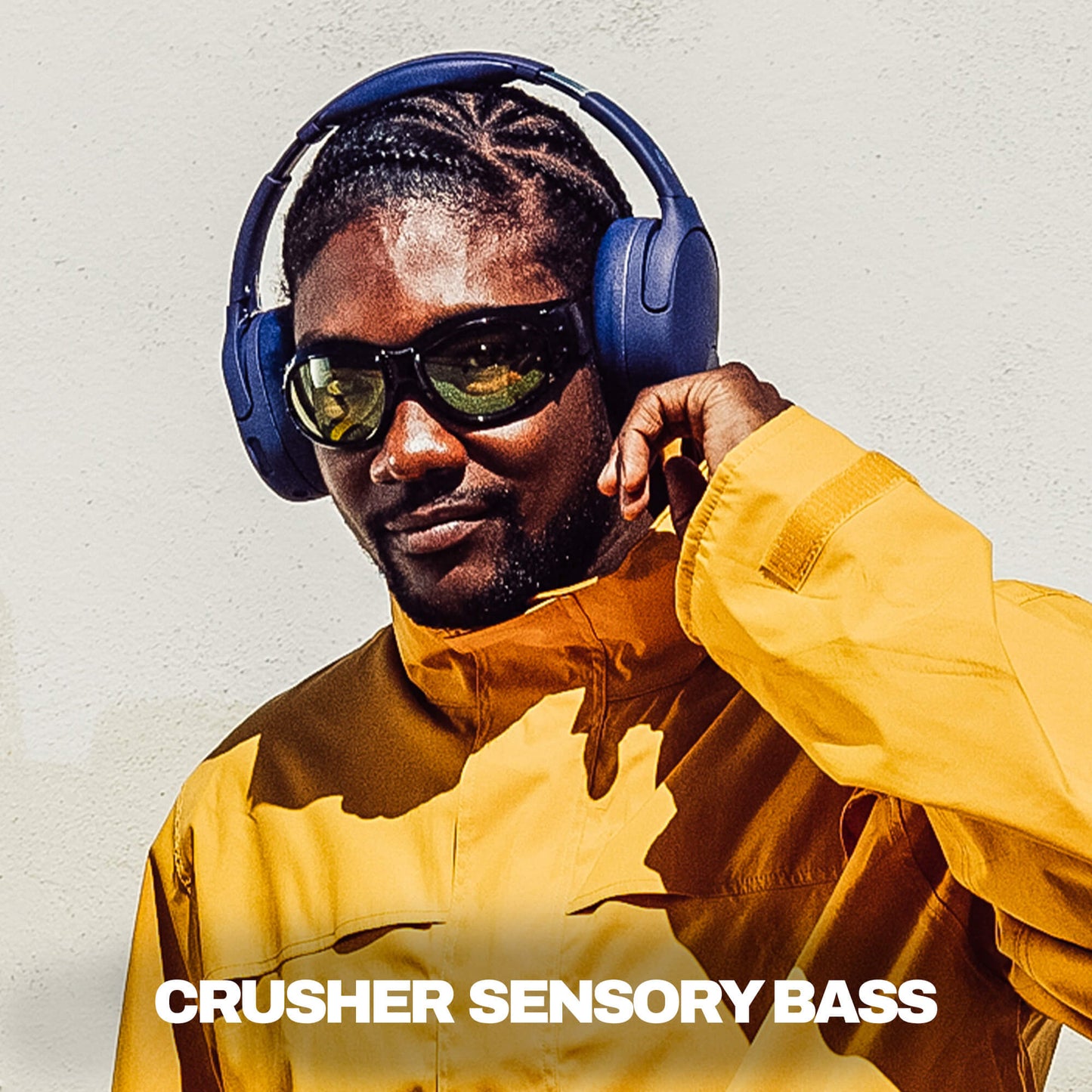 Man wearing blue Crusher 720 headphones and yellow jacket with 'Crusher Sensory Bass' text.