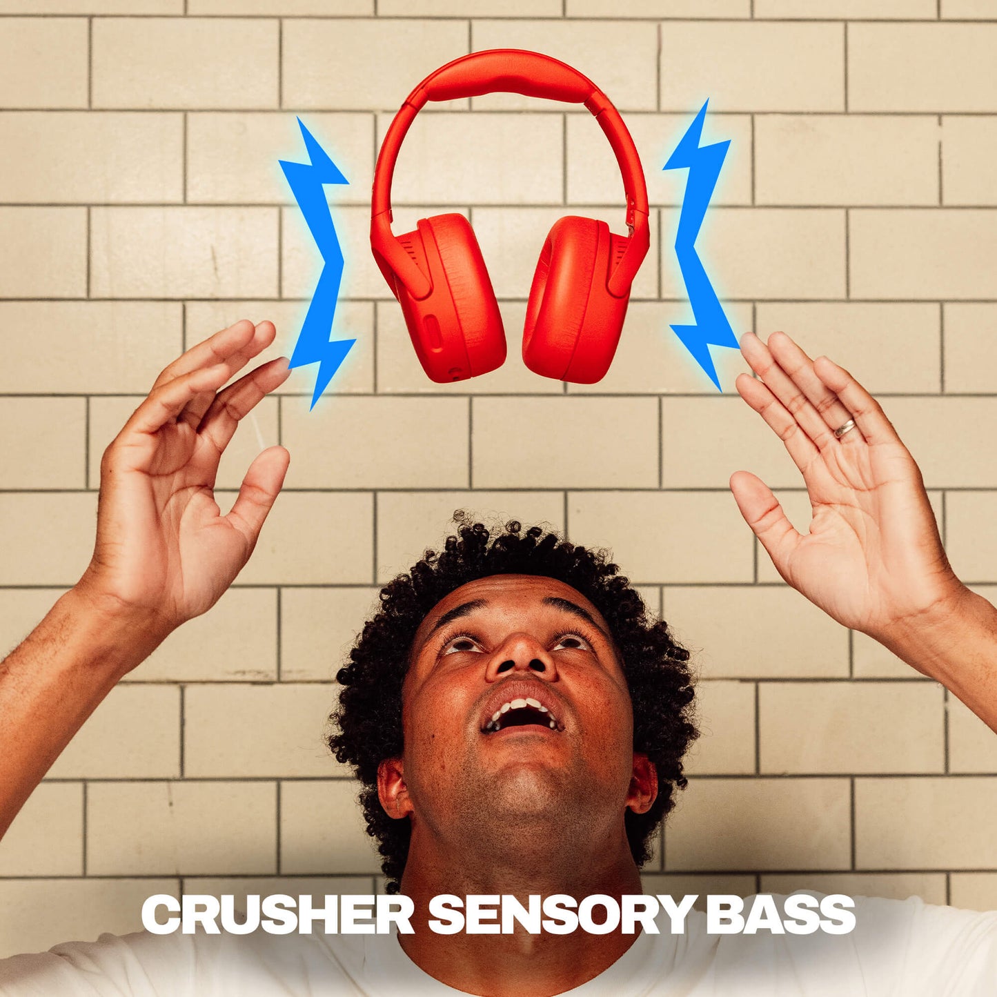 Person with red Crusher 720 headphones and blue lightning bolts against a tiled wall, with 'Crusher Sensory Bass' text. | Plasma
