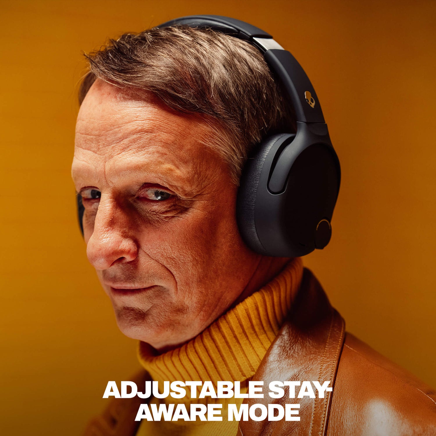 Tony Hawk wearing Crusher 720 headphones with text 'Adjustable Stay Aware Mode' on a warm-toned background | True Black