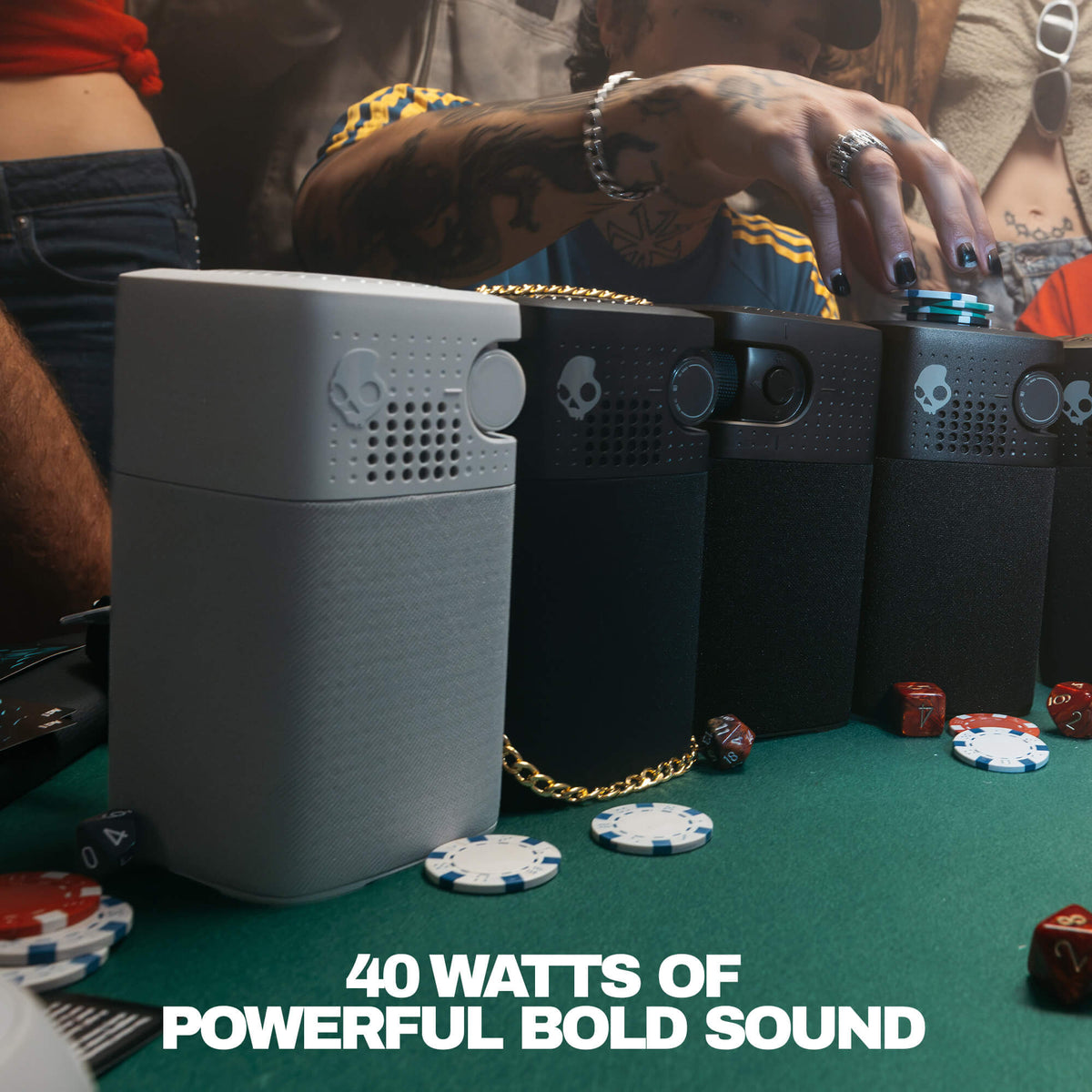 A woman wearing dark sunglasses holds a session 900 speaker in one hand while taking a selfie with a smartphone. Other people are visible in the background, and the text 'BUILT-IN POWER BANK' appears at the bottom. | Primer