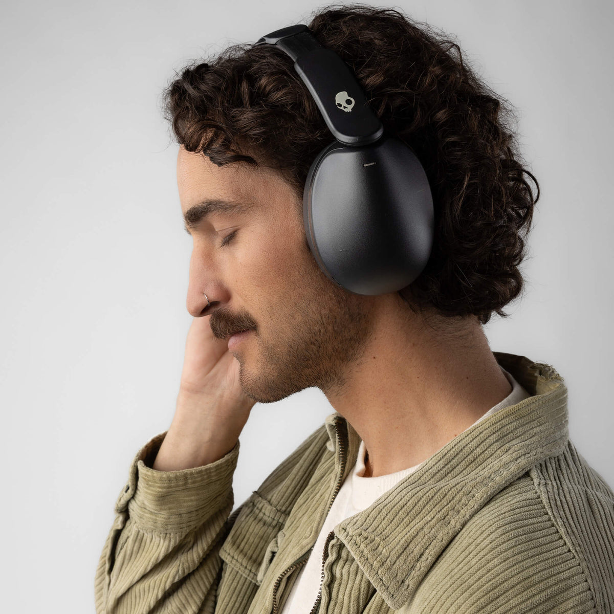 Man wearing black hesh 360 headphones with a neutral background | True Black
