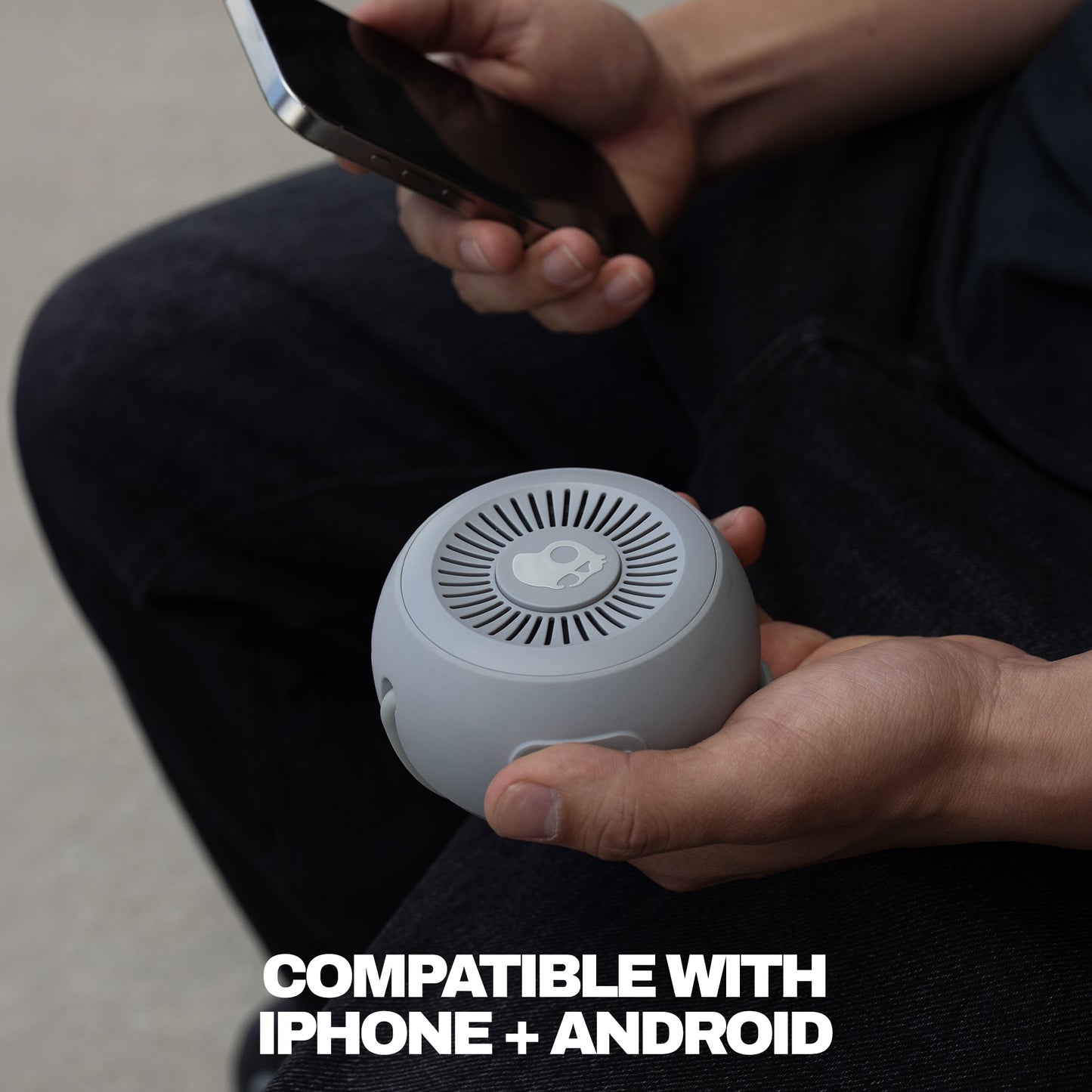 Person holding a small white device with text indicating compatibility with iPhone and Android. | Cement
