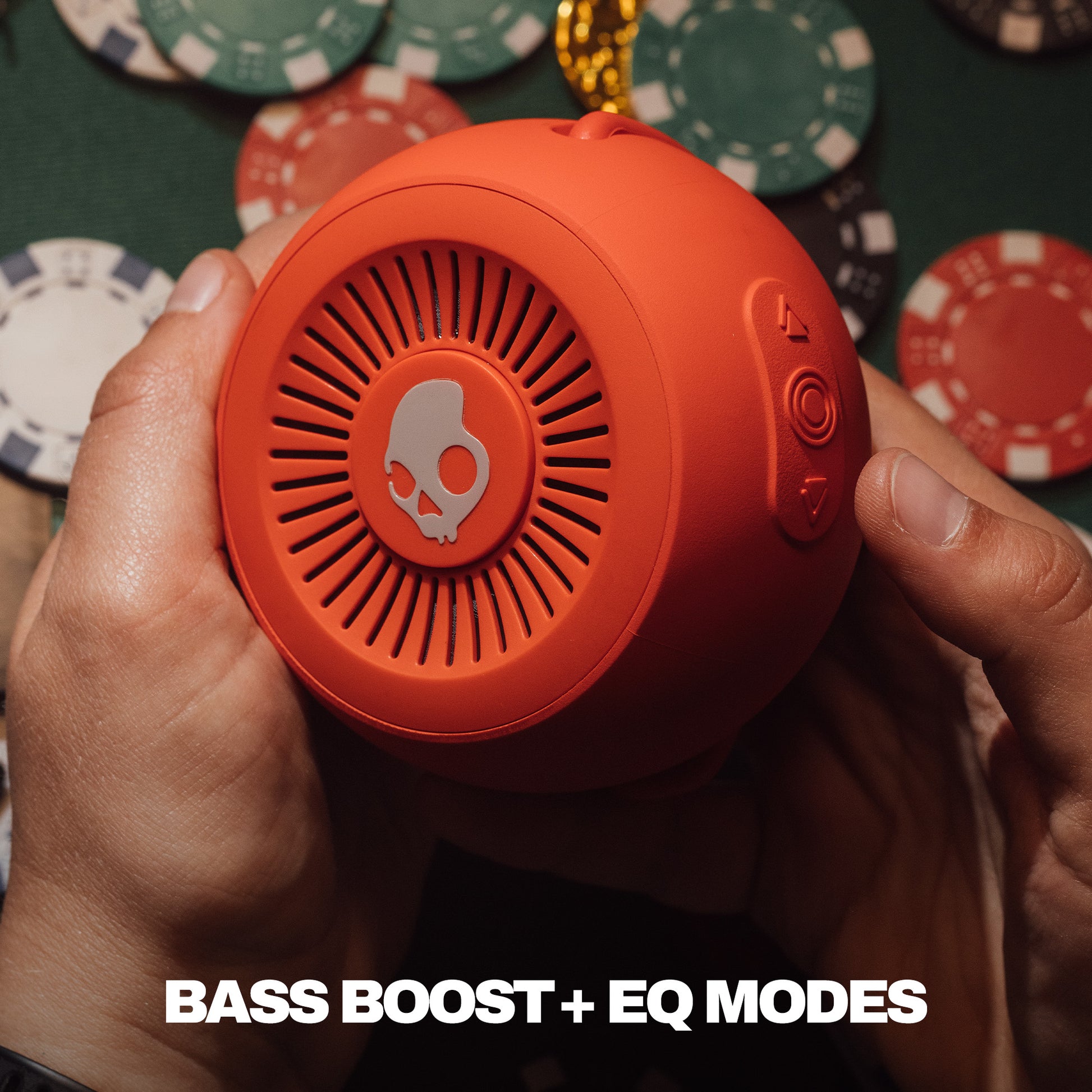 Person holding an orange portable speaker with poker chips in the background | Plasma