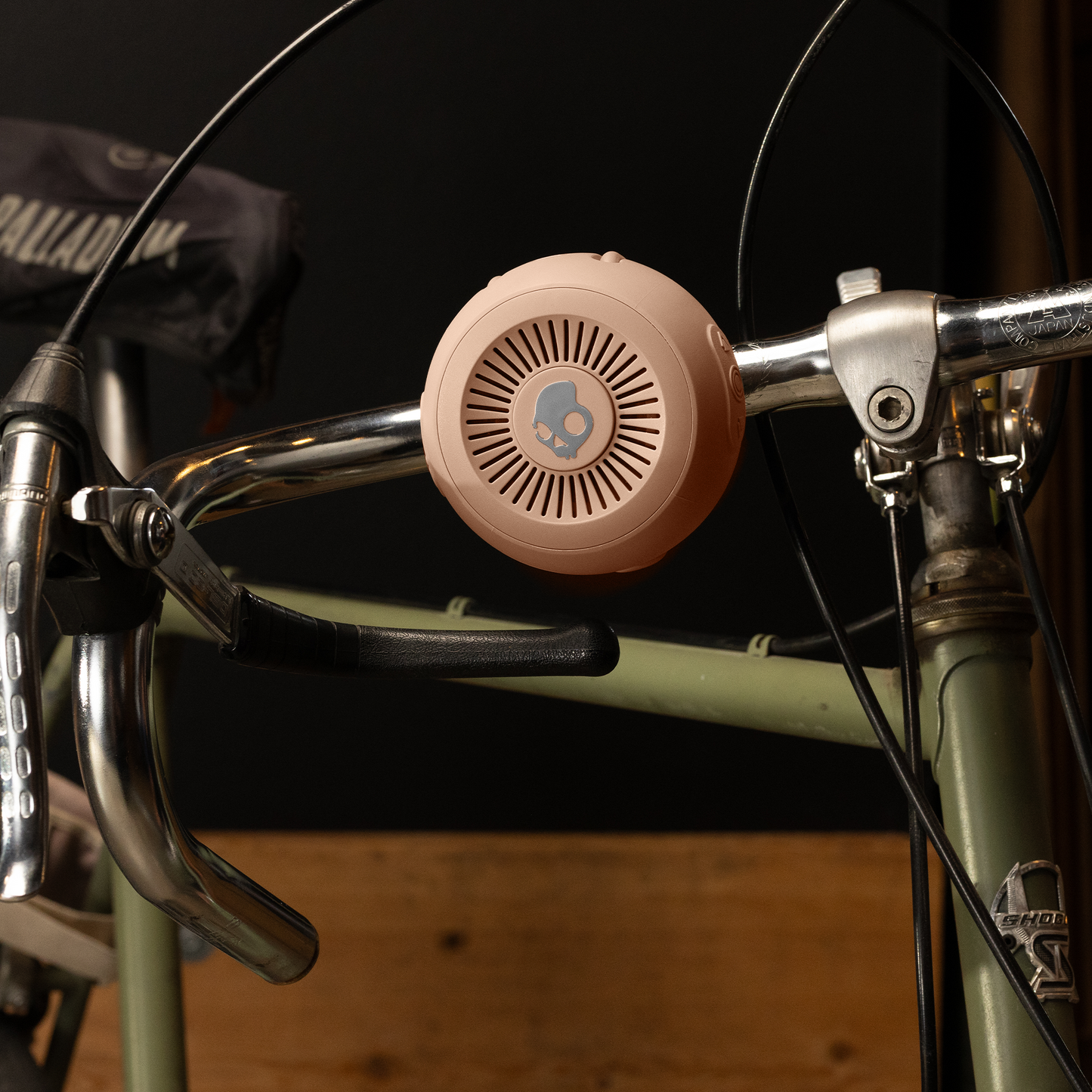 Pink speaker attached to a bike handlebar with a dark background | Primer