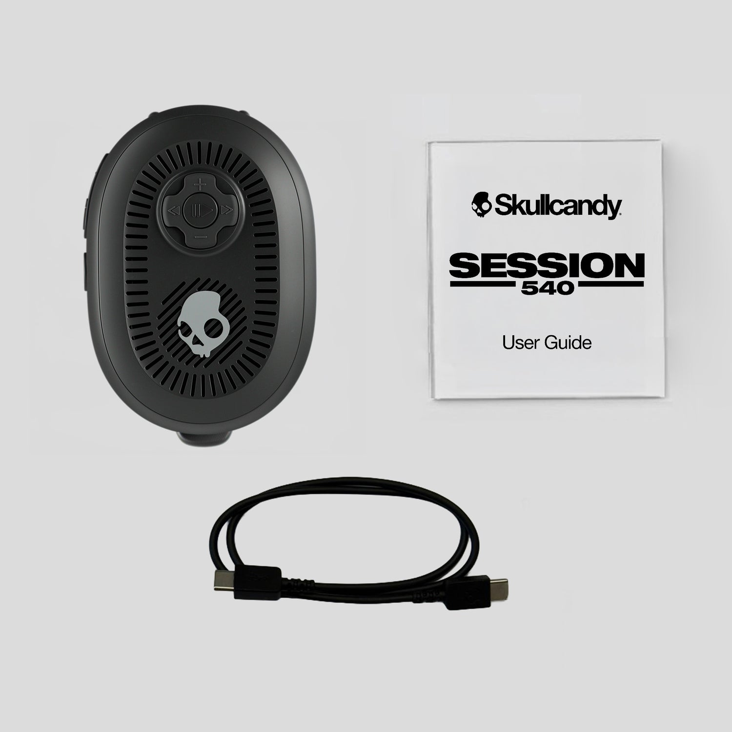 Black electronic speaker with cable and Skullcandy user guide on a light gray background | Cement