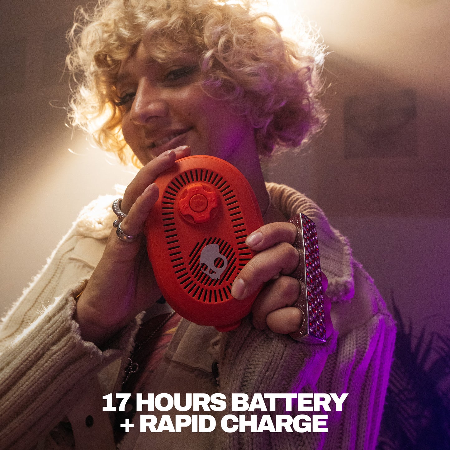 Person holding a red speaker with text about battery life and charging speed. | Plasma