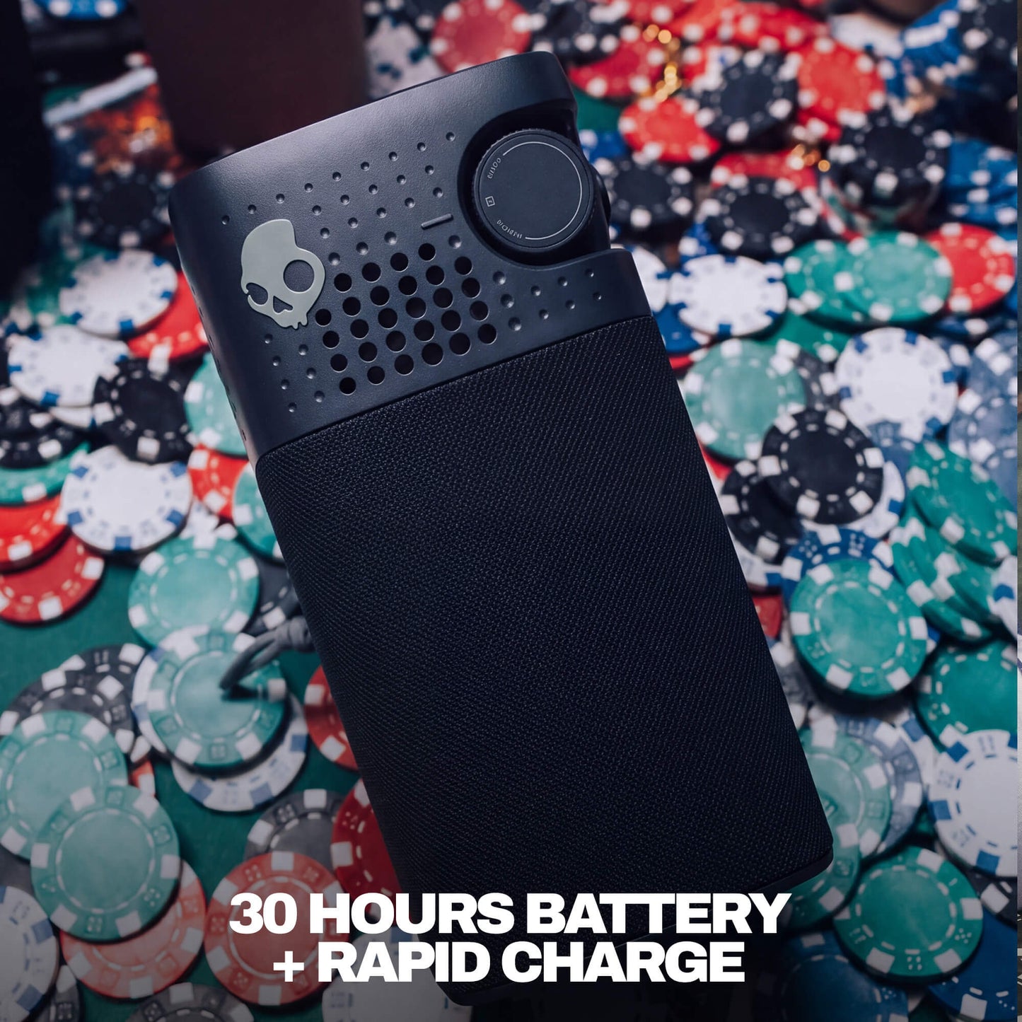 A black session 900 with a skull logo, resting on a pile of colorful poker chips. White text at the bottom reads '30 HOURS BATTERY + RAPID CHARGE'. | True Black