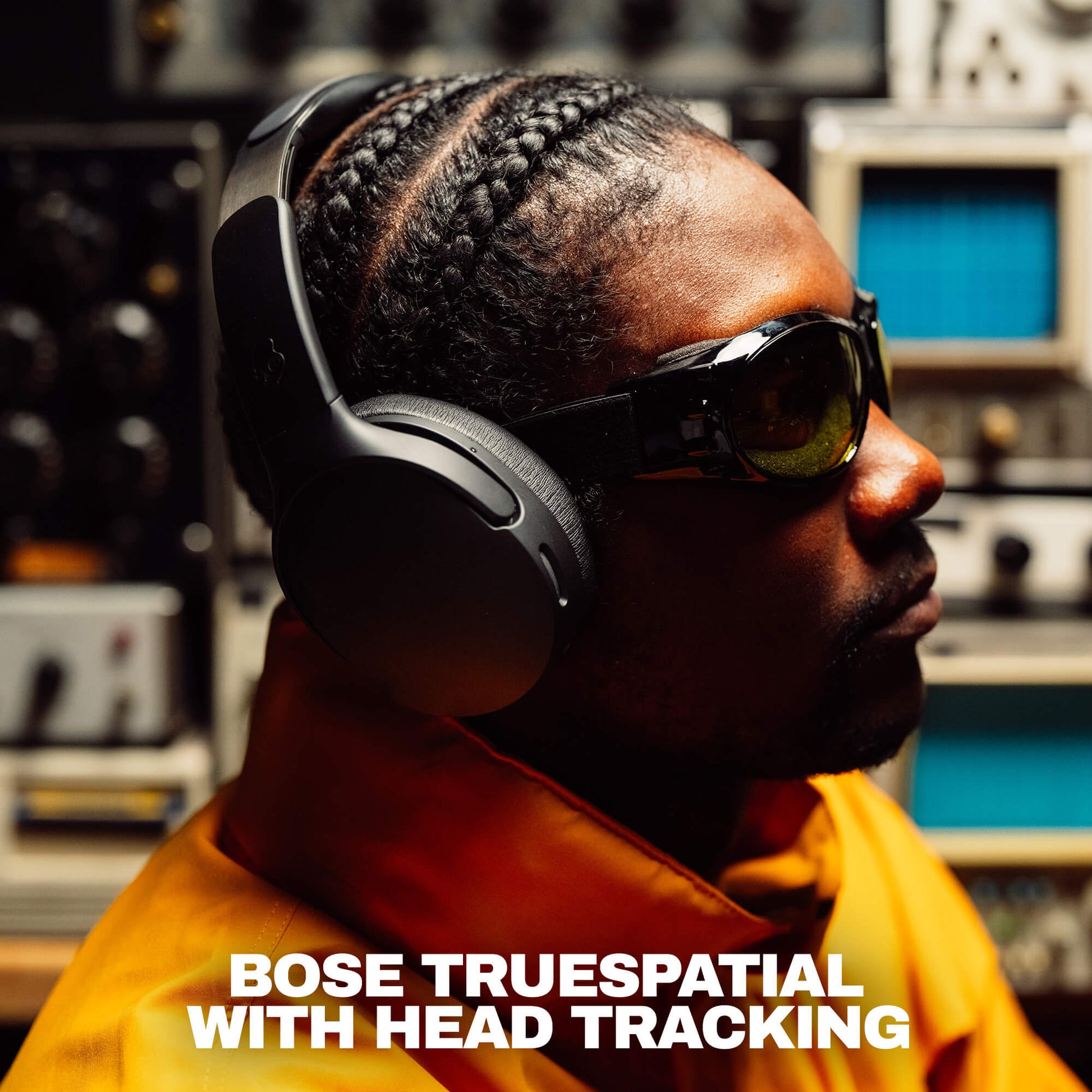 A man in profile wearing black Bose headphones with head tracking and dark sunglasses, set against a blurred studio background with audio equipment. White text at the bottom reads 'BOSE TRUESPATIAL WITH HEAD TRACKING'. | True Black