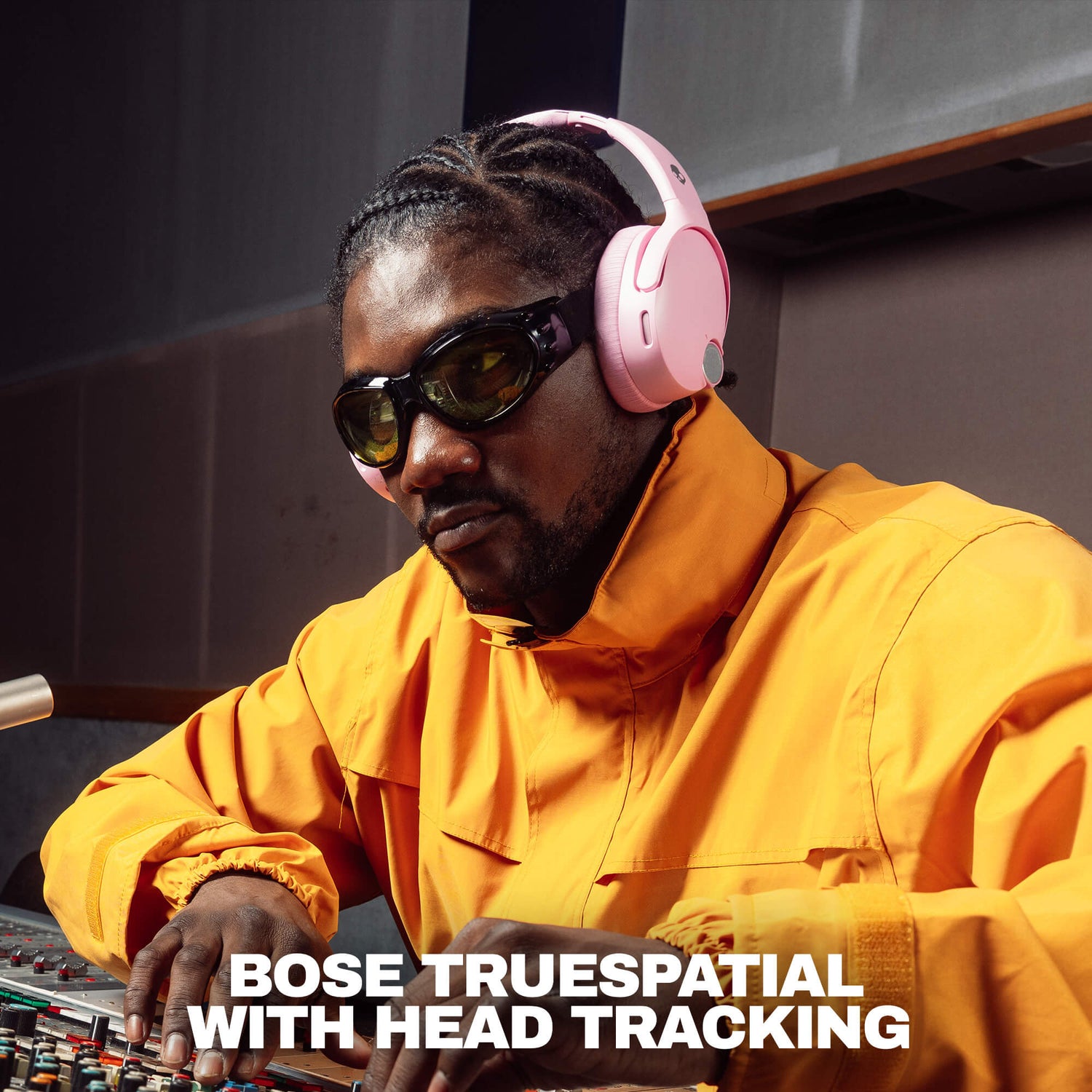 A man in a recording studio wearing pink Bose TrueSpatial headphones with head tracking, a bright yellow jacket, and dark sunglasses, with the text 'BOSE TRUESPATIAL WITH HEAD TRACKING' at the bottom. | Candy