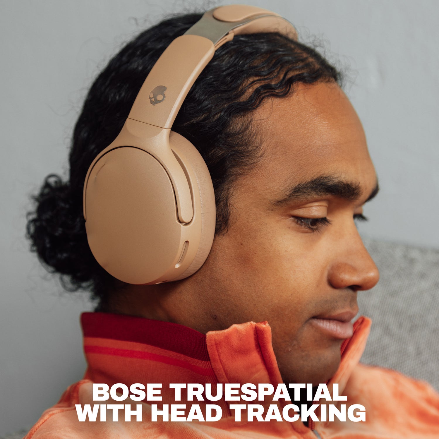 A man wearing beige Bose TrueSpatial over-ear headphones with head tracking, shown in profile against a neutral gray background with promotional text at the bottom. | Primer