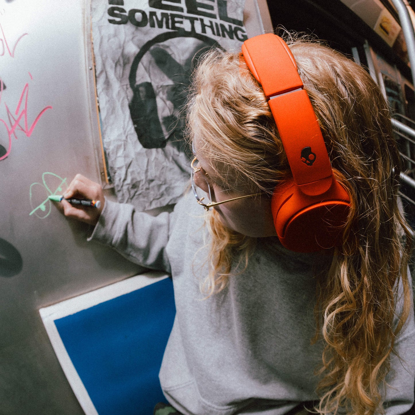 Person wearing red Crusher 720 headphones writing on a whiteboard with a graphic design in the background. | Plasma
