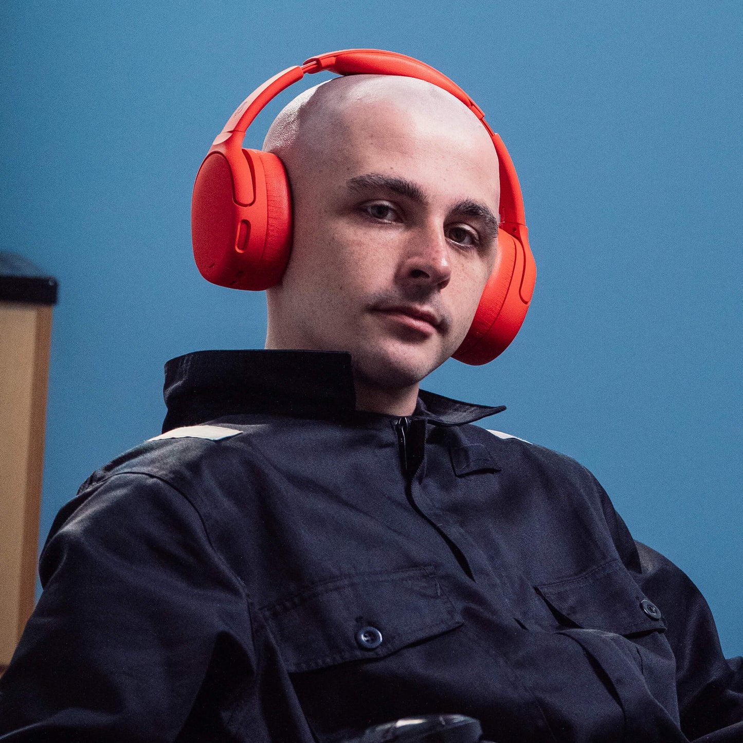 Man wearing red Crusher 720 headphones against a blue background | Plasma