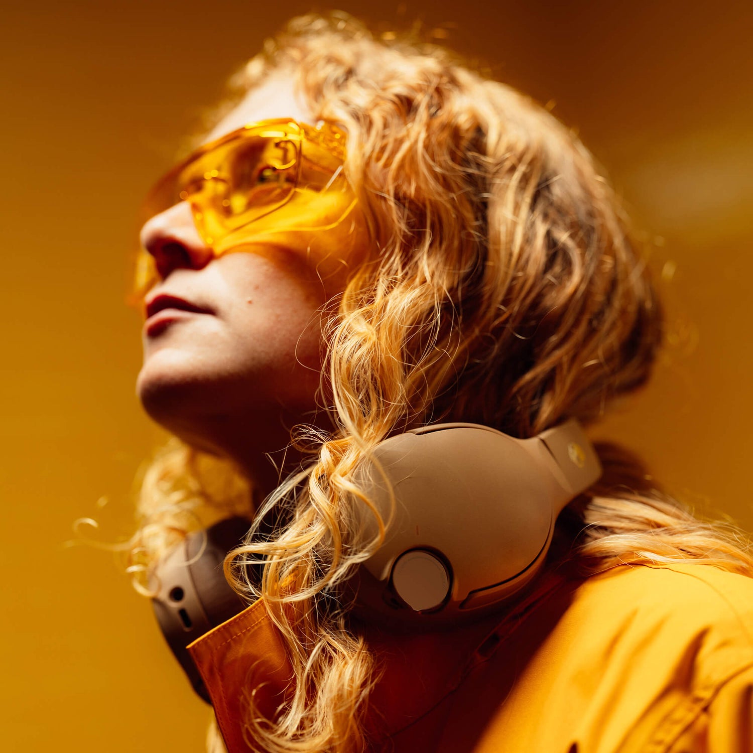 Person wearing yellow sunglasses and a brown Cruseh 720 headset against an orange background | Primer